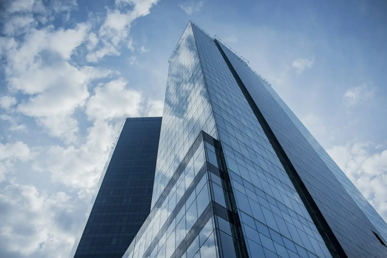 A glass office tower rising into the clouds