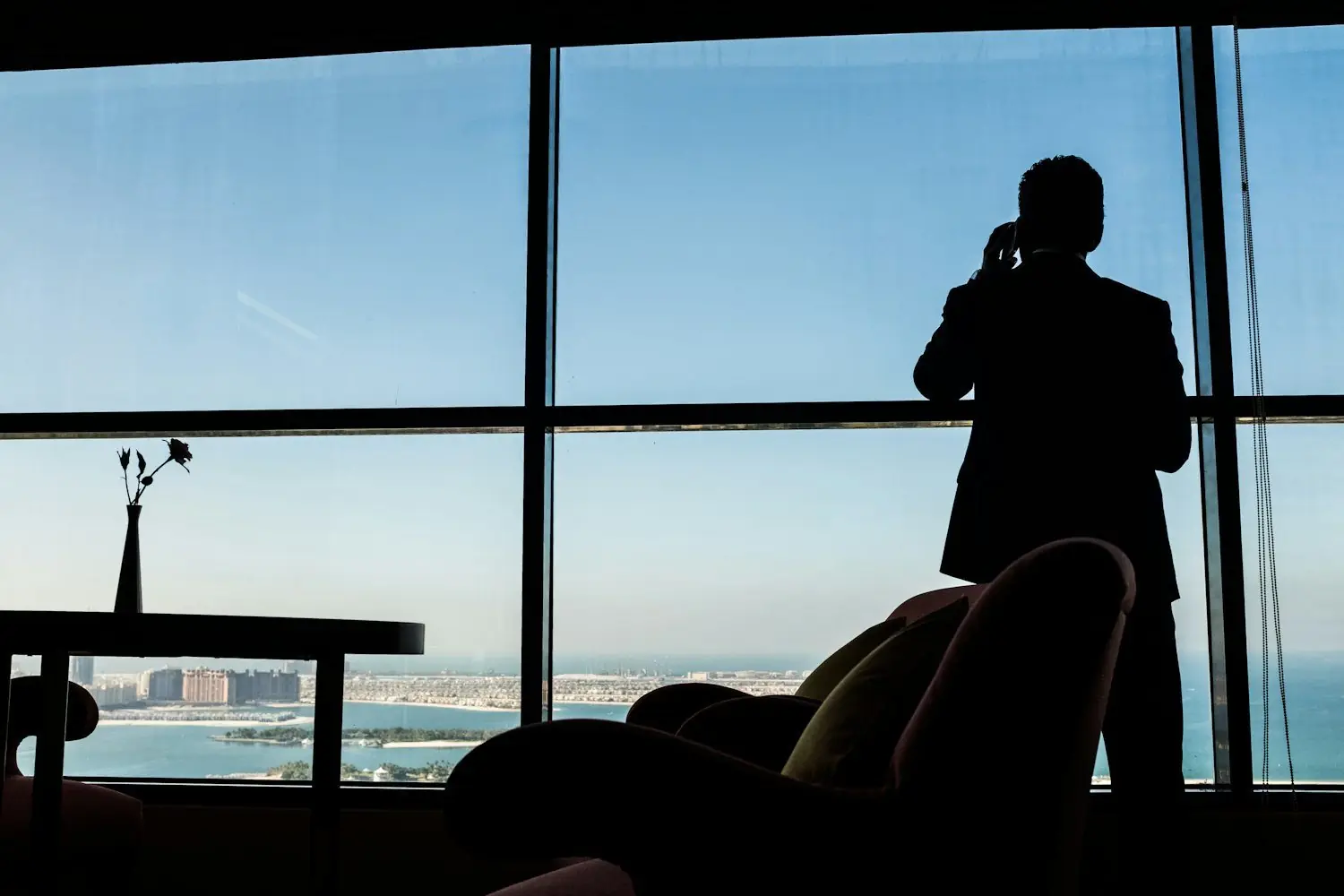 A founder on a call by a window overlooking the Gulf